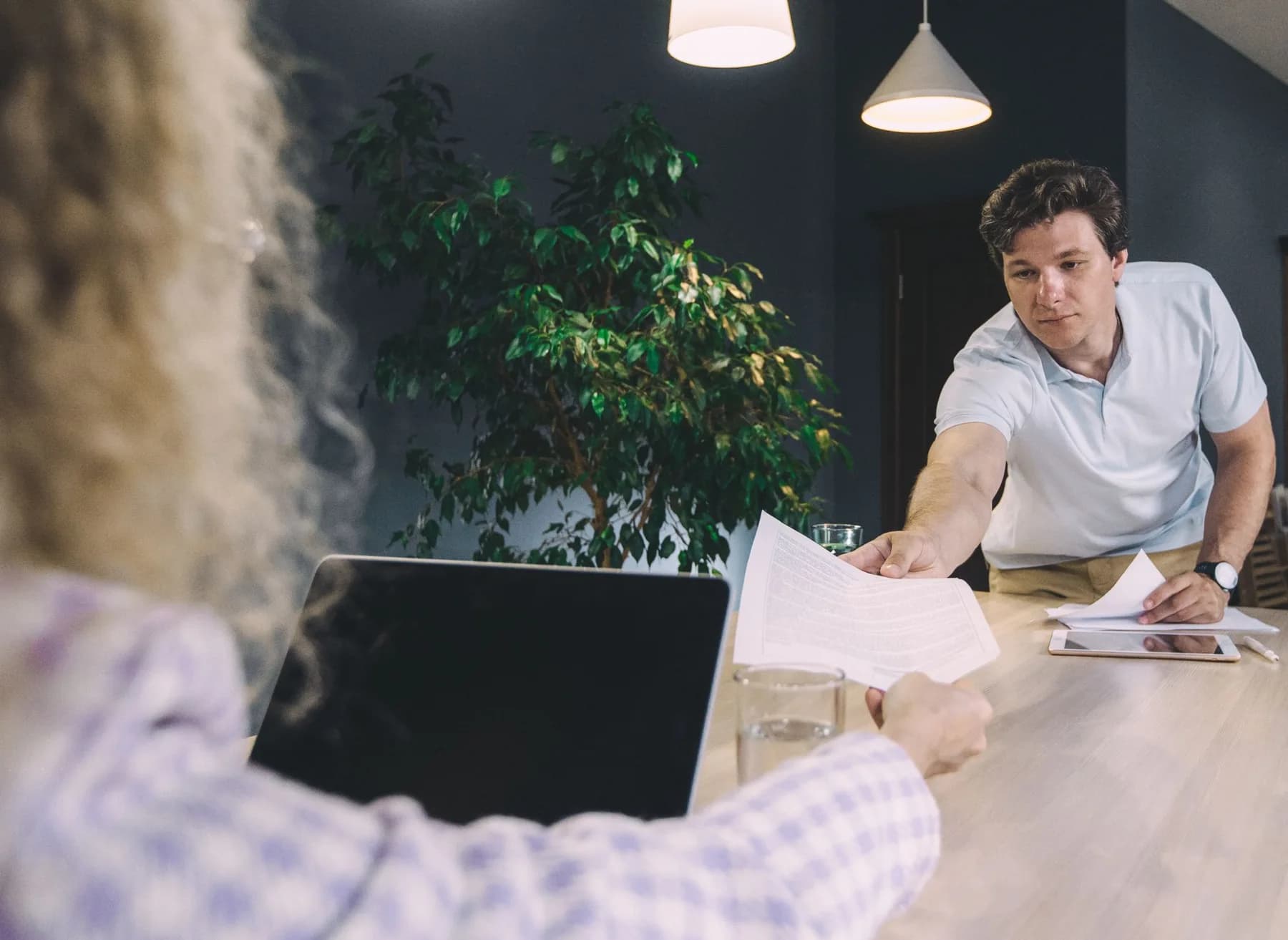 Twee collega’s geven met aandacht werkdocumenten aan elkaar door.